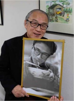 ラーメンを食べる往時の写真を手にする鈴木伸一